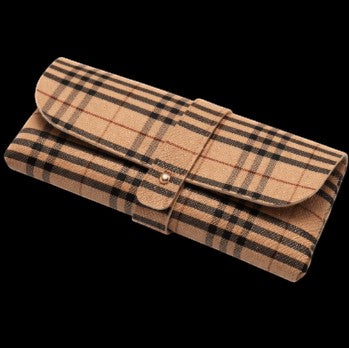 Petey's jewelry luxury glasses case in a tan, black, and red plaid pattern with a secure snap button closure.
