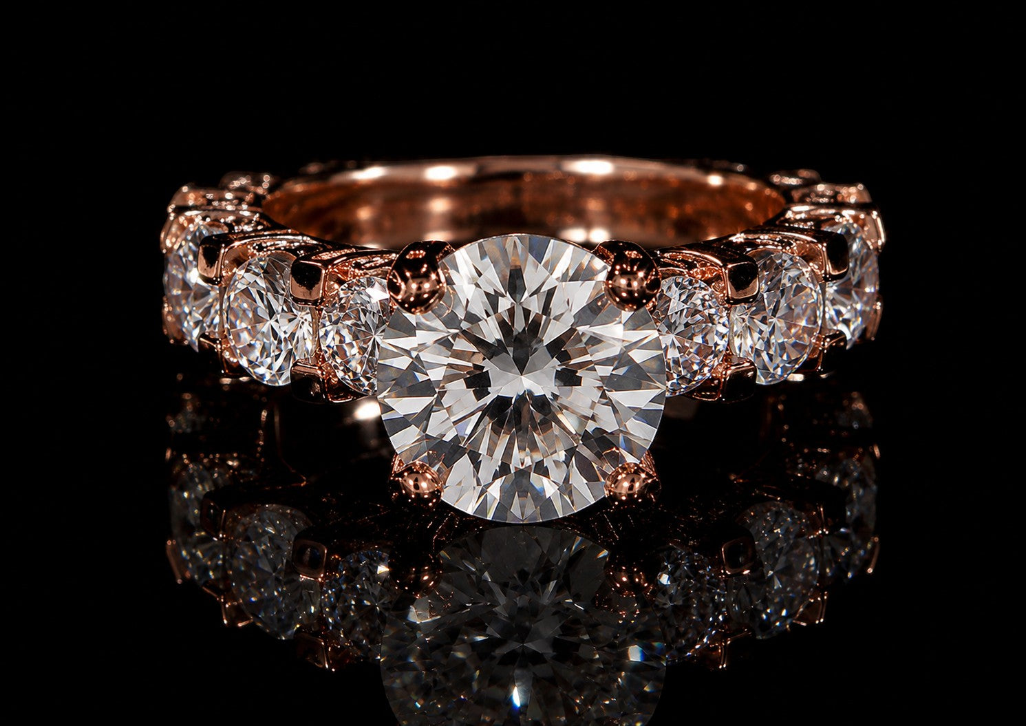 Petey's jewelry rose gold 925 silver ring with a large round brilliant cut moissanite center stone and smaller stones along the band.